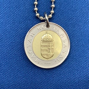 May include: A silver chain necklace with a silver and gold coin pendant. The coin features the Hungarian coat of arms and the text "MAGYAR KÖZTÁRSASÁG 1998".
