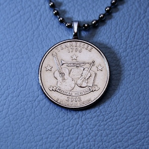 May include: Silver necklace with a Tennessee quarter coin pendant featuring a guitar, trumpet, violin, and the words "Musical Heritage 2002".