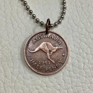 May include: A copper-colored pendant necklace featuring a 1943 Australian half penny coin with a kangaroo design. The coin reads "AUSTRALIA" and "HALF PENNY" around the edge. The coin is attached to a silver chain.