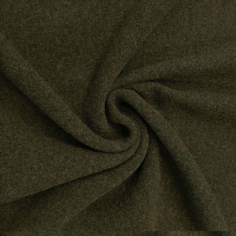 May include: A close-up of a dark green fabric with a soft, fuzzy texture. The fabric is folded and draped, showing its drape and texture.