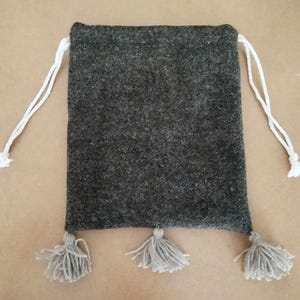Peut inclure: Un sac à cordon en feutre gris avec des cordons de serrage blancs et trois pompons gris.