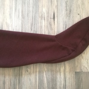 Puede incluir: Una bota larga de tela color burdeos con punta.