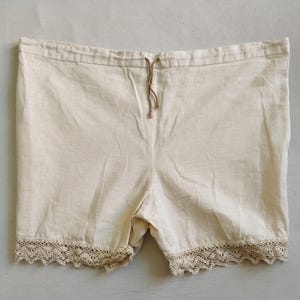 Peut inclure: Shorts en lin de couleur crème, avec une taille à cordon et une délicate bordure en dentelle. Ces shorts ont une coupe décontractée et une esthétique vintage. Leur couleur neutre et leur design simple les rendent polyvalents.