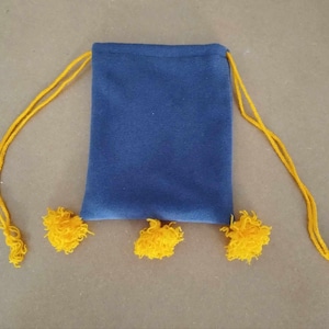Peut inclure: Un petit sac à cordon bleu avec des pompons jaunes. Le sac est fait d'un tissu doux et duveteux.