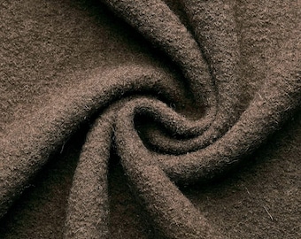 May include: Close-up of a brown, soft, and textured fabric. The fabric is folded and draped, showing its texture and drape.