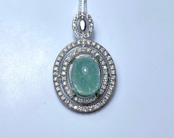 May include: A silver pendant necklace with a large oval-shaped green gemstone surrounded by a double row of clear cubic zirconia stones.