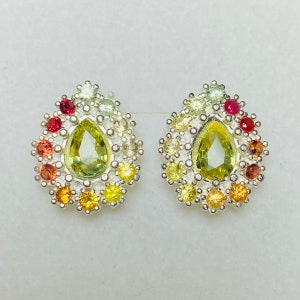 May include: A pair of silver earrings featuring a pear-shaped green gemstone surrounded by smaller colourful gemstones.