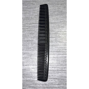 May include: A black plastic comb with fine teeth. The comb is about 7 inches long.