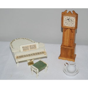 May include: A white miniature piano with a music sheet on the top, a green cushioned stool, a white pitcher and bowl, and a wooden grandfather clock with a clock face.