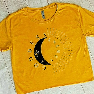May include: A yellow cropped t-shirt with a black crescent moon graphic and the text "Goddess Energy" in a circular design.