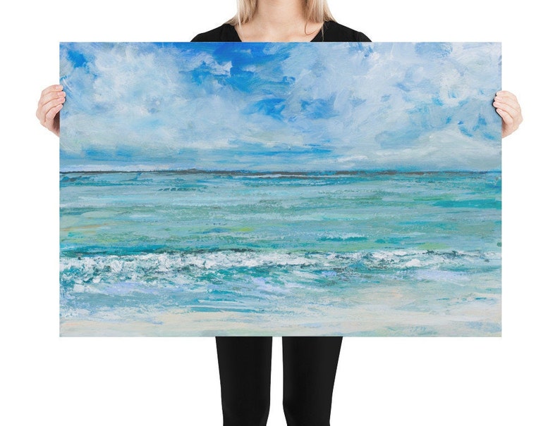 Op de afbeelding: Een schilderij van een zeelandschap met een blauwe lucht en witte wolken. De oceaan is lichtblauw met witte golven die aan de kust breken.
