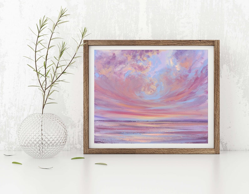 May include: A framed painting of a pink and purple sunset over a calm body of water. The sky is filled with fluffy clouds, and the water reflects the colors of the sky.
