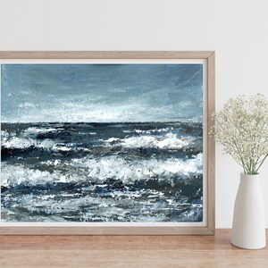 May include: A framed painting of a seascape with blue and white waves crashing against a dark blue ocean. The sky is a light blue with white clouds.