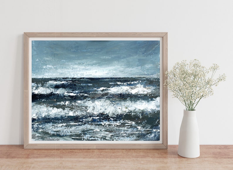 May include: A framed painting of a seascape with blue and white waves crashing against a dark blue ocean. The sky is a light blue with white clouds.