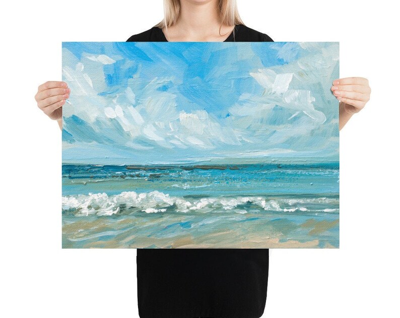 May include: A painting of a seascape with blue water and white clouds in a light blue sky. The waves are crashing on the sandy beach.