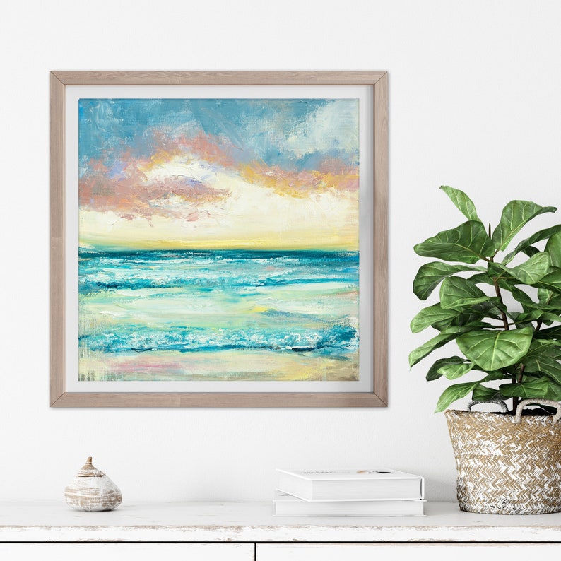 Puede incluir: Una pintura enmarcada de un paisaje mar&iacute;timo con un oc&eacute;ano azul y verde, olas blancas espumosas y un cielo de puesta de sol rosa y amarillo.