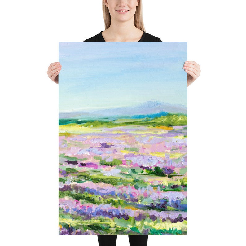 Op de afbeelding: Een schilderij van een veld met paarse bloemen met een bergketen op de achtergrond. De lucht is blauw en de bloemen zijn geschilderd in een losse, impressionistische stijl.