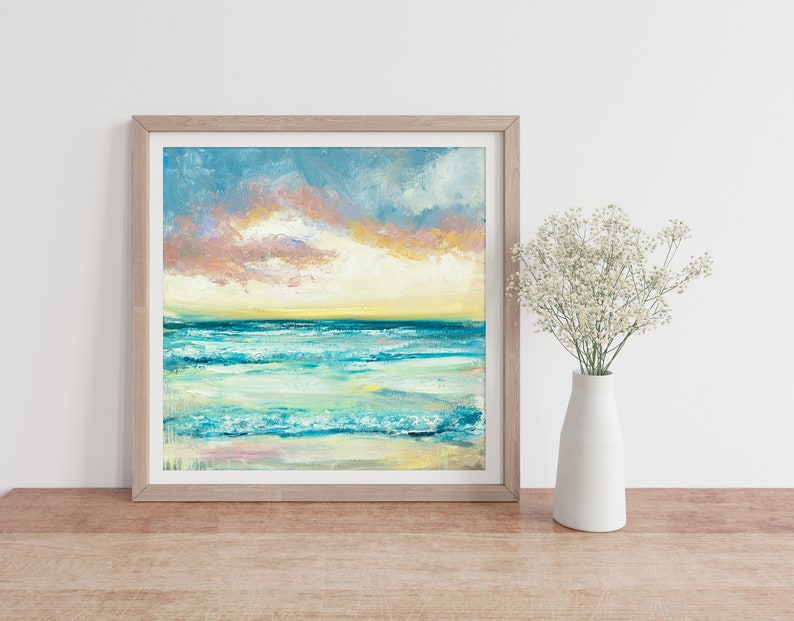 Puede incluir: Una pintura enmarcada de un paisaje mar&iacute;timo con un oc&eacute;ano azul y verde, olas blancas y un cielo de puesta de sol rosa y amarillo.