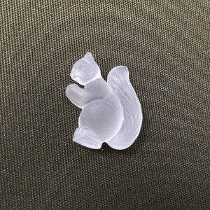 May include: A white glass squirrel figurine with a bushy tail. The figurine is detailed with a small nose and eyes.