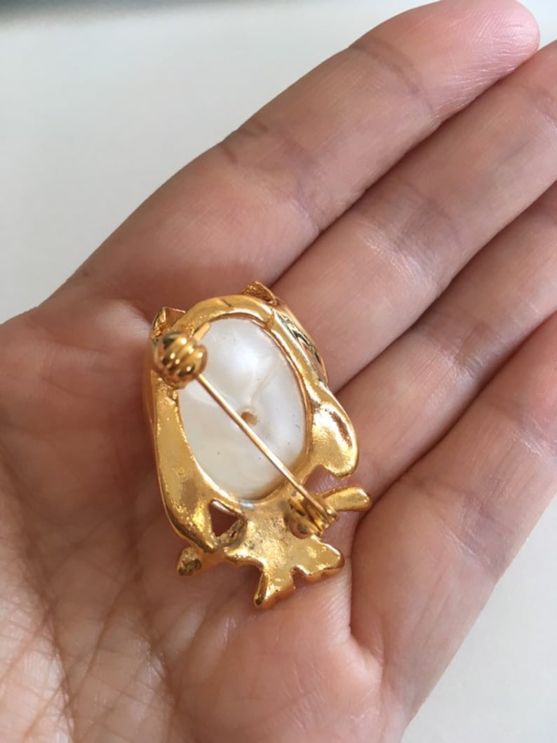 Peut inclure: Broche en forme de hibou dor&eacute;e avec un cabochon ovale blanc au centre. La broche a un fermoir &agrave; &eacute;pingle.