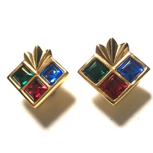Puede incluir: Un par de pendientes de tono dorado con un dise&ntilde;o cuadrado. Cada pendiente tiene cuatro piedras cuadradas en rojo, verde y azul.