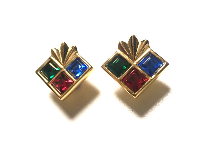 Puede incluir: Un par de pendientes de tono dorado con un dise&ntilde;o cuadrado. Cada pendiente tiene cuatro piedras cuadradas en rojo, verde y azul.