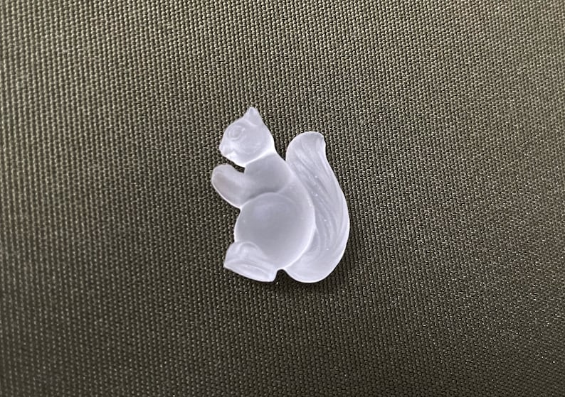 May include: A white glass squirrel figurine with a bushy tail. The figurine is detailed with a small nose and eyes.