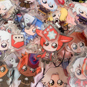 Puede incluir: Una colección de dijes de personajes de anime coloridos con diferentes diseños. Los dijes están hechos de plástico transparente y presentan varios personajes con ojos grandes y colores brillantes. Algunos de los dijes tienen burbujas de diálogo con texto.