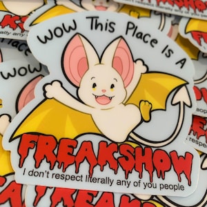 Puede incluir: Una pegatina con un murciélago de dibujos animados en crema, rosa y amarillo. El texto de la pegatina dice "WOW This Place Is A FREAKSHOW" en negro y rojo, con la frase "I don't respect literally any of you people" debajo.