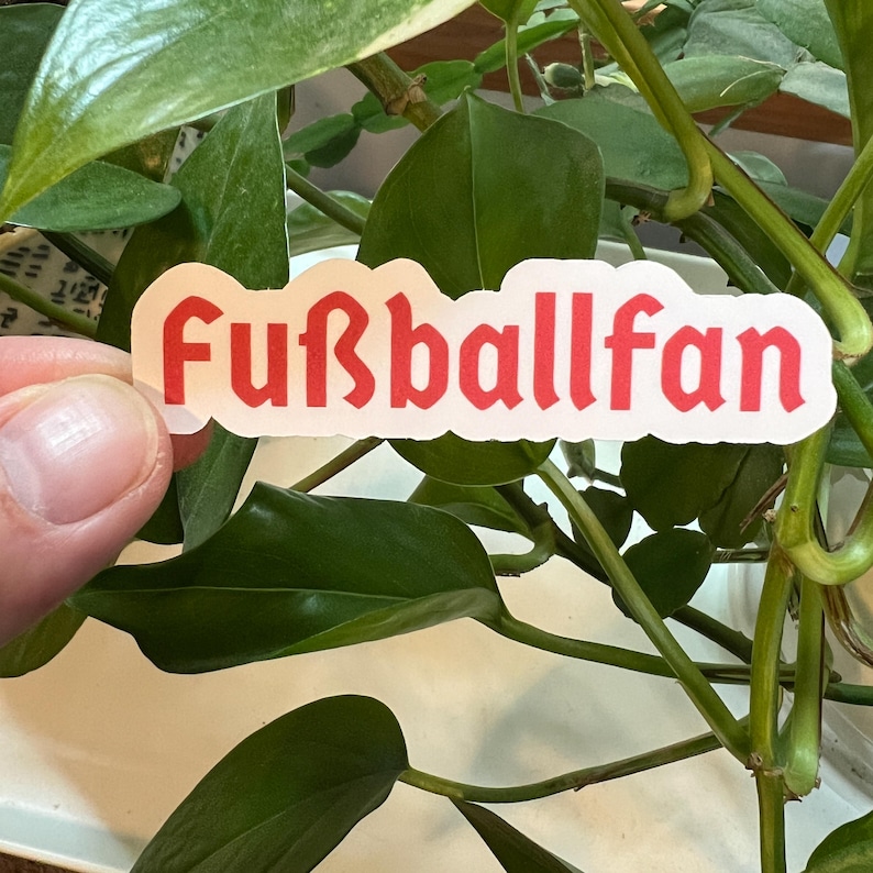 May include: White sticker with the word "Fu&szlig;ballfan" in red gothic lettering.