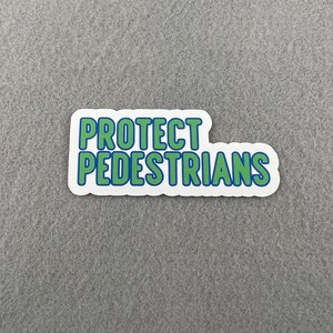 May include: A white sticker with blue and green text that reads "PROTECT PEDESTRIANS".