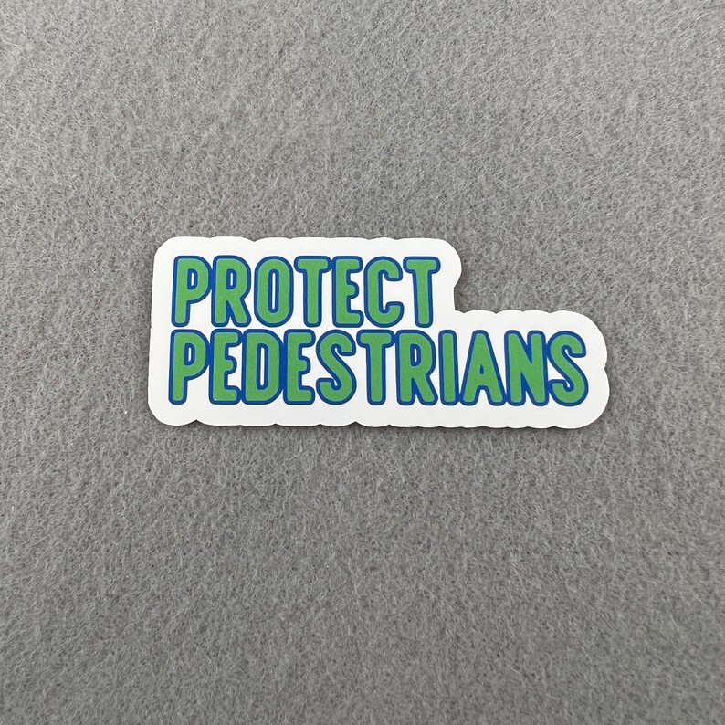 May include: A white sticker with blue and green text that reads "PROTECT PEDESTRIANS".