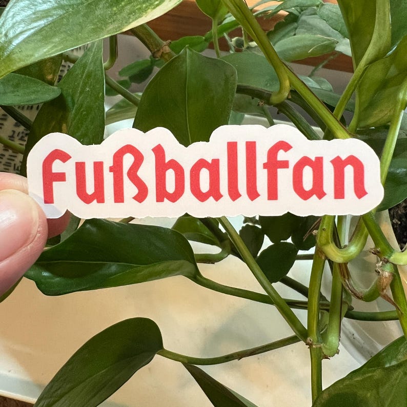 May include: A white sticker with the word "Fu&szlig;ballfan" written in red gothic font.