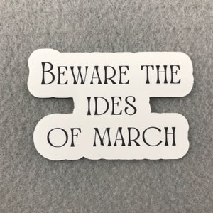 May include: White sticker with black text that reads "Beware the Ides of March".