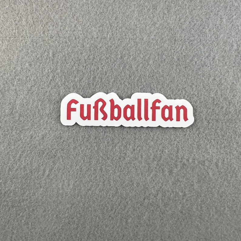May include: White sticker with the word "Fu&szlig;ballfan" in red lettering.