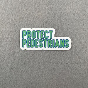 May include: White sticker with blue and green text that reads "PROTECT PEDESTRIANS".