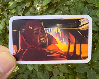 May include: A rectangular sticker featuring a stylized illustration of a person dressed as a devil with red skin, small horns, and a goatee, holding a black trident. The background shows a fiery orange and yellow glow, creating a high-contrast scene.