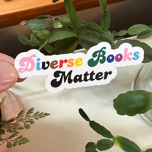 May include: A sticker with the text "Diverse Books Matter" in a rainbow of colors. The words are in a retro font style.