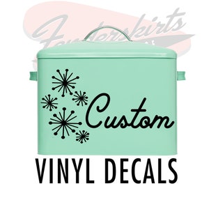 May include: A mint green metal storage box with a black vinyl decal of a stylized starburst design and the word "Custom". The box has a silver handle and is labeled "Vinyl Decals".