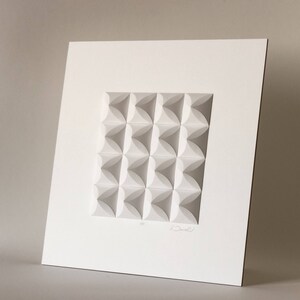 May include: White paper sculpture with a geometric pattern of overlapping circles. The sculpture is framed and signed by the artist.