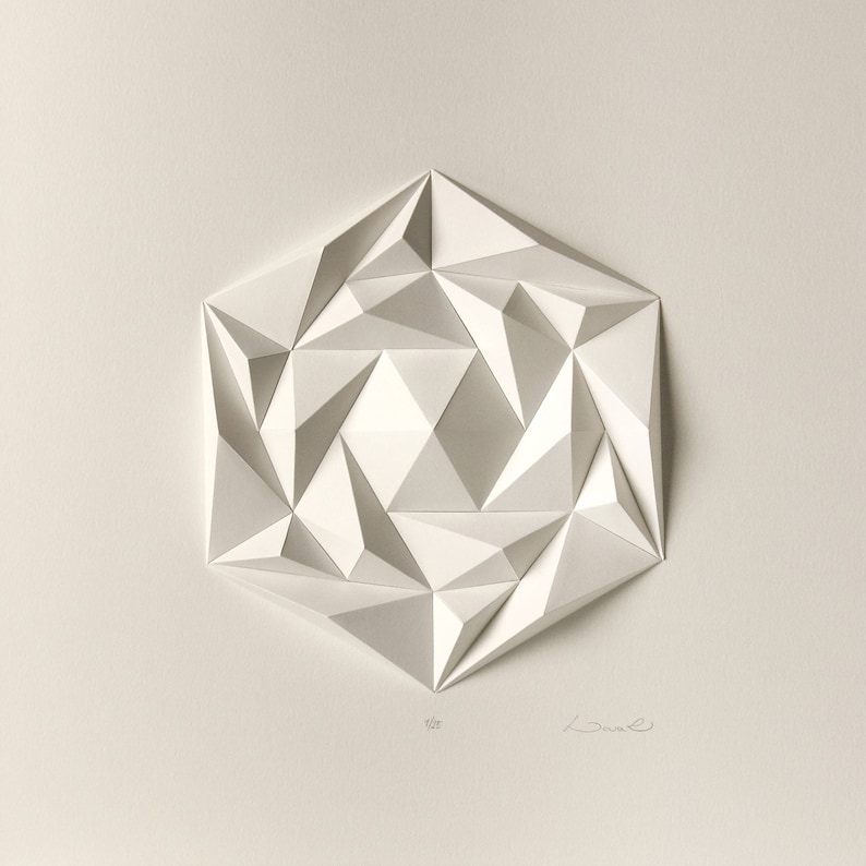 May include: A white paper sculpture of a geometric shape with a hexagonal base and a complex, three-dimensional design. The sculpture is made of many small triangles that are folded and layered to create a sense of depth and movement.