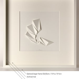 May include: A white framed artwork featuring a white paper sculpture of geometric shapes. The artwork is matted and has an optional larger frame available in 19 3/4 x 19 3/4 inches.