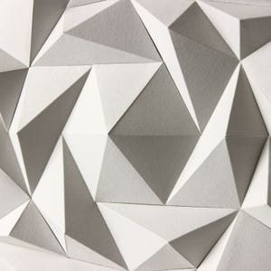 May include: A geometric pattern of white and gray triangles, creating a textured, three-dimensional effect.