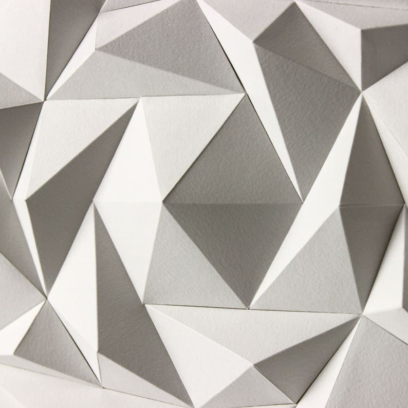 May include: A geometric pattern of white and gray triangles, creating a textured, three-dimensional effect.