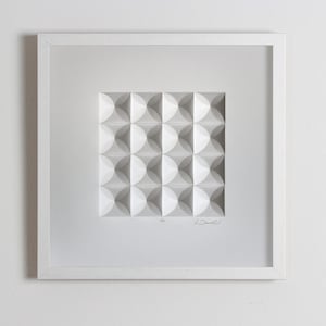 May include: A white framed artwork featuring a geometric pattern of white circles in a square shape. The artwork is signed "Drew" in the bottom right corner.