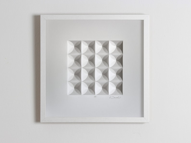 May include: A white framed artwork featuring a geometric pattern of white circles in a square shape. The artwork is signed "Drew" in the bottom right corner.