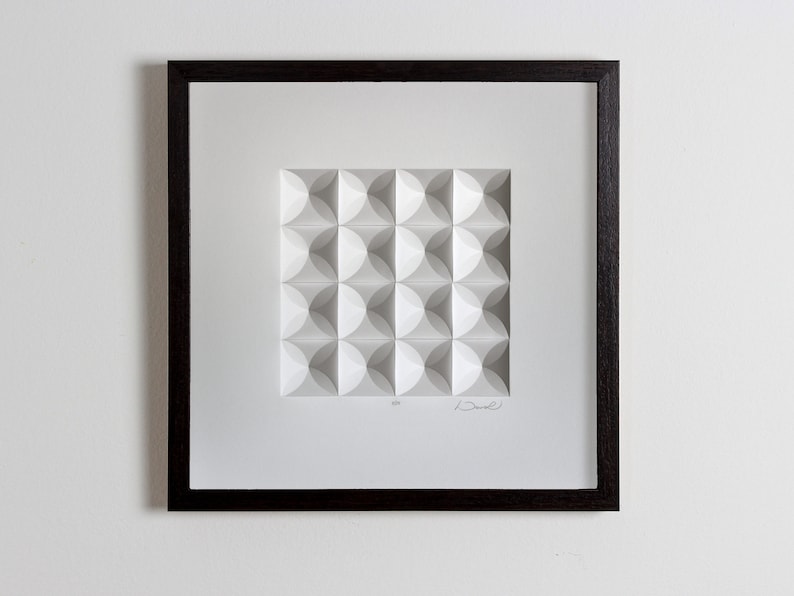 May include: A framed white paper sculpture with a geometric pattern of overlapping circles. The sculpture is signed "Drew" and numbered "4/25".