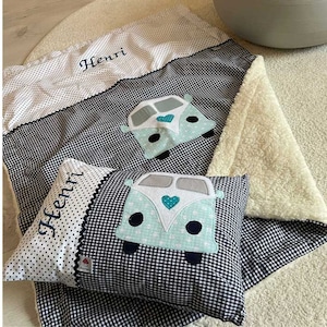 Könnte beinhalten: Eine weiße und schwarze karierte Babydecke mit einer weißen Fleece-Rückseite. Die Decke zeigt einen blauen und grünen gestickten Van mit einem Herzen auf der Vorderseite. Die Decke trägt auch den Namen "Henri" gestickt.