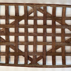 May include: A brown woven basket with a rectangular shape and a slightly rounded edge. The basket is made of natural wood and has a grid pattern.