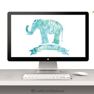 May include: A desktop computer with a blue and green watercolor elephant on the screen. The elephant has the words "Dream Big" written on it. The text "You've Got This" is written on a banner below the elephant. The computer is on a white desk with a green lamp and a white mouse.